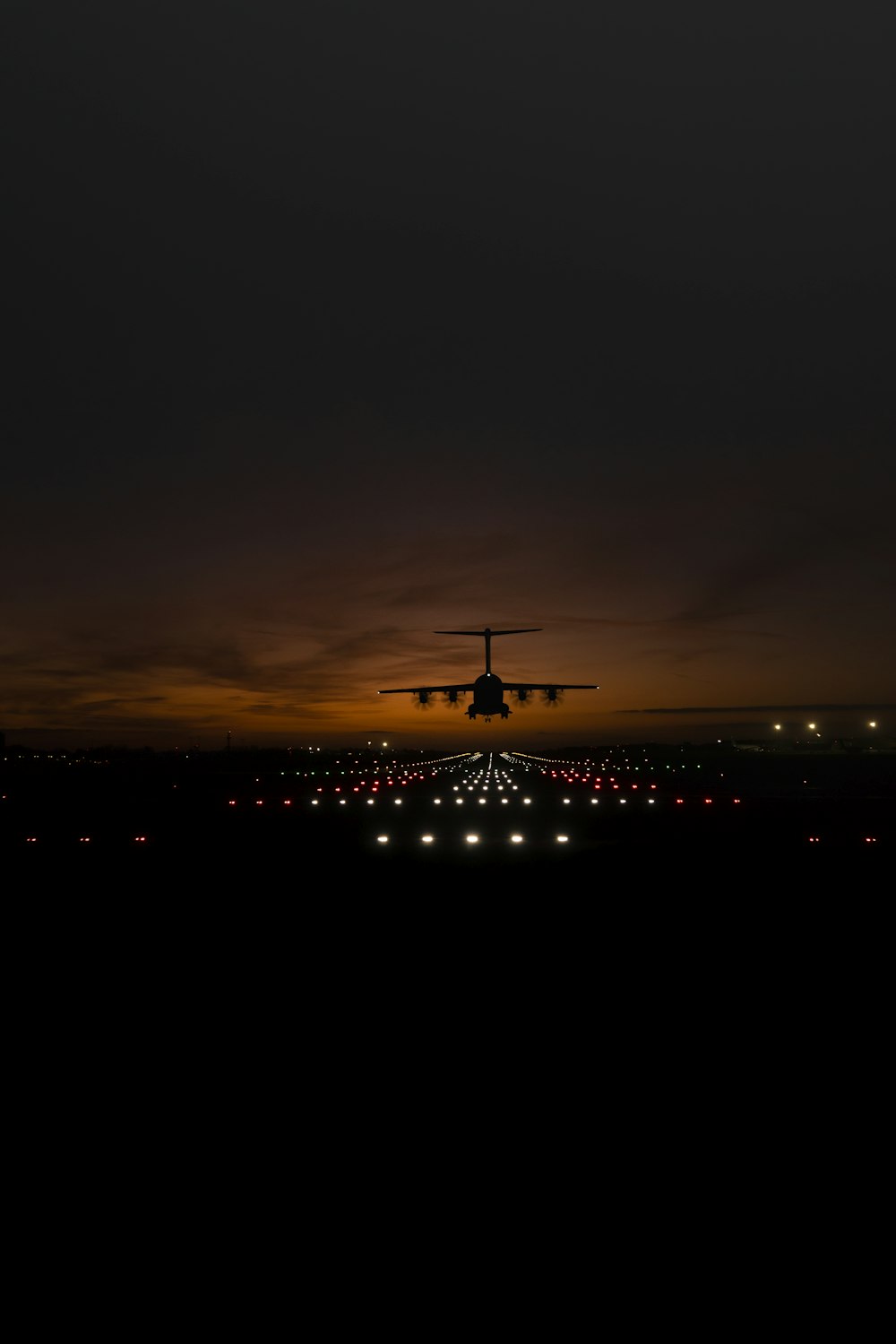 a large jetliner flying over a runway at night