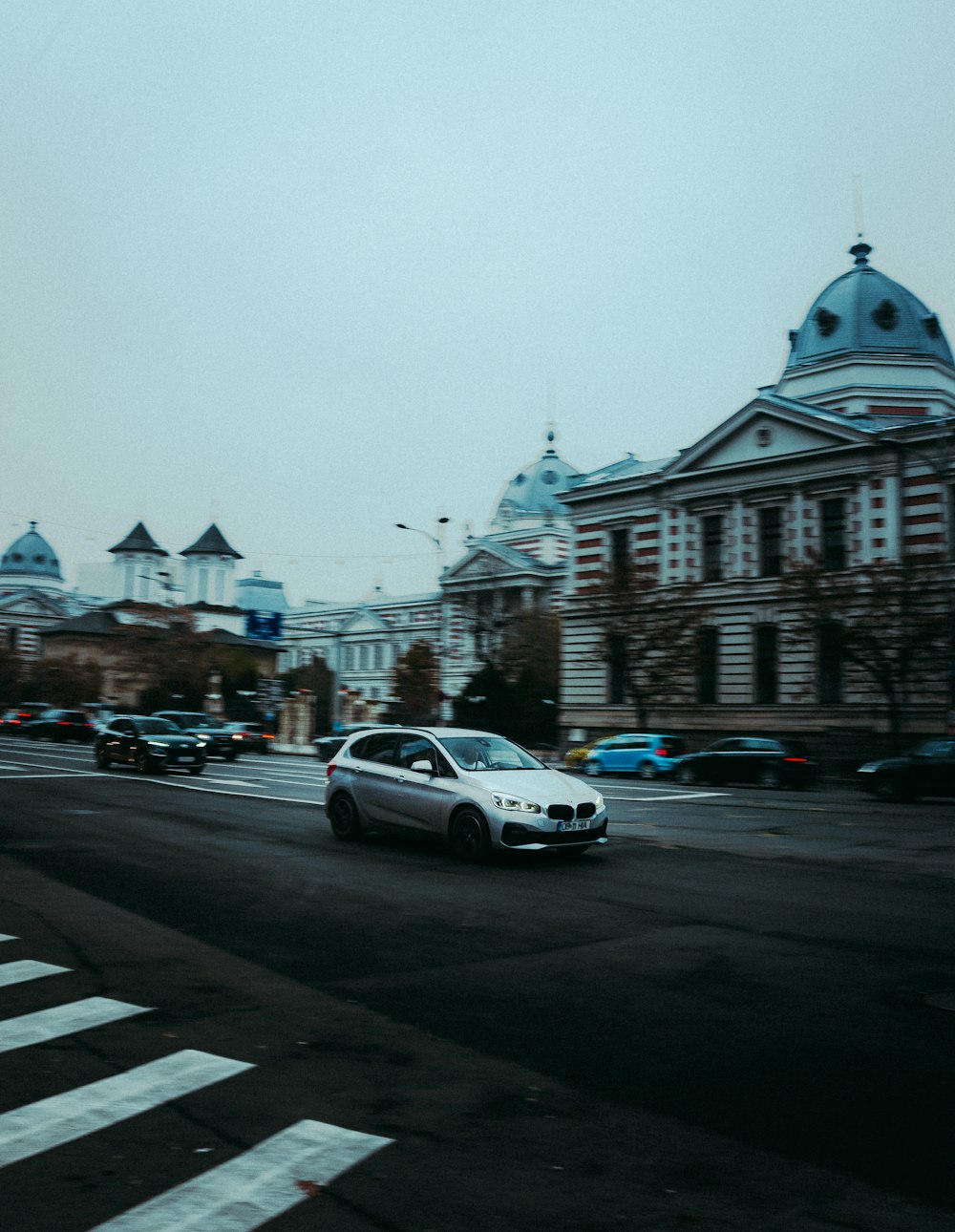 a white car driving down a street next to tall buildings