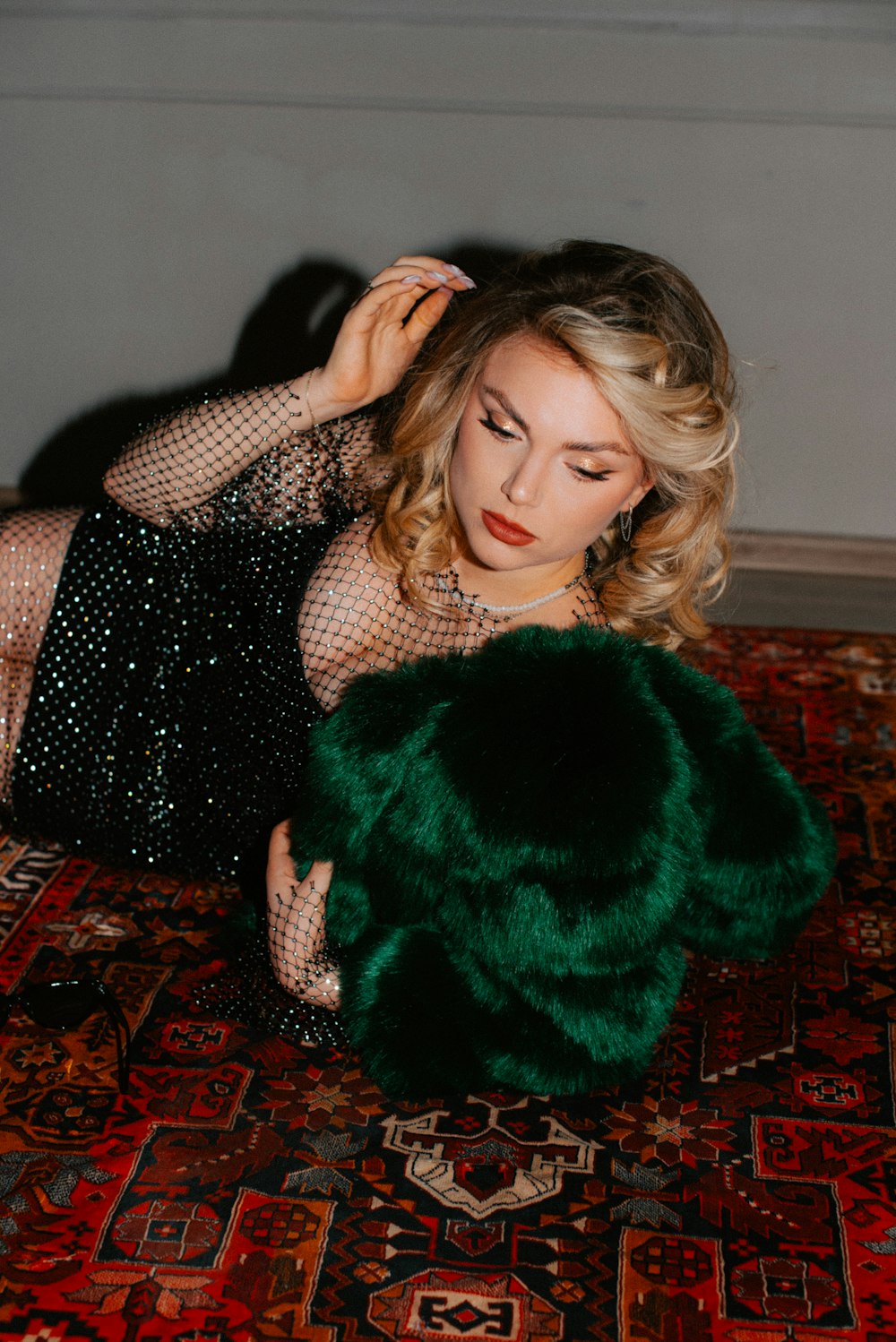 a woman in a black dress and green fur coat