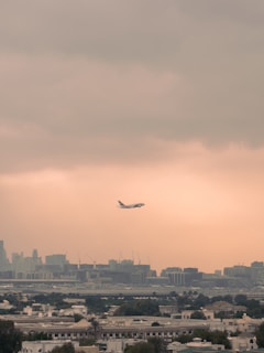 An airplane taking off over a city skyline with soft morning light.