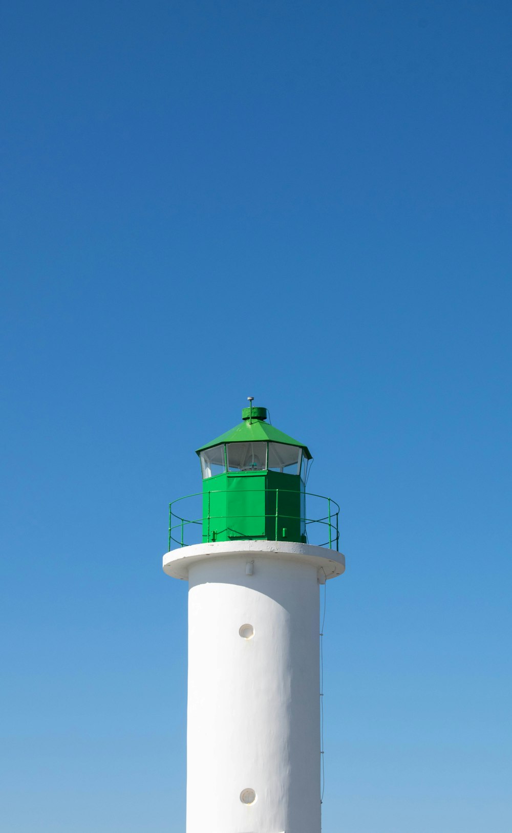 a white and green lighthouse on a clear day
