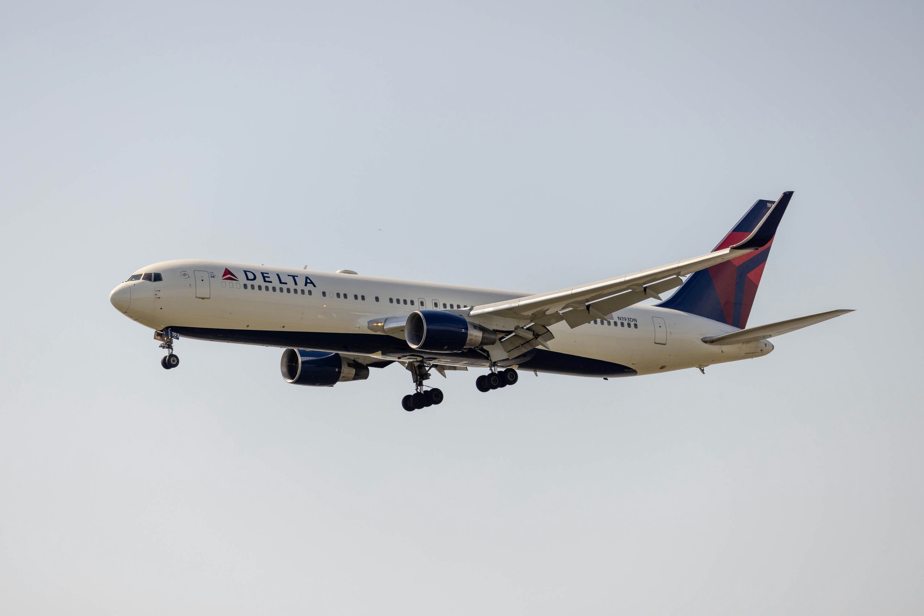 a delta airlines plane flying in the sky, Left side of a Boeing 777 by Delta Airlines in flight with landing gear pulled out.