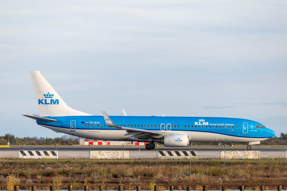 a large blue and white jetliner sitting on top of an airport runway