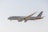 A commercial airplane in flight, displaying the American Airlines livery with red, white, and blue stripes on the tail. The aircraft's landing gear is extended, indicating preparation for landing. It flies against a clear, pale blue sky.