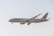 A commercial airplane in flight, displaying the American Airlines livery with red, white, and blue stripes on the tail. The aircraft's landing gear is extended, indicating preparation for landing. It flies against a clear, pale blue sky.