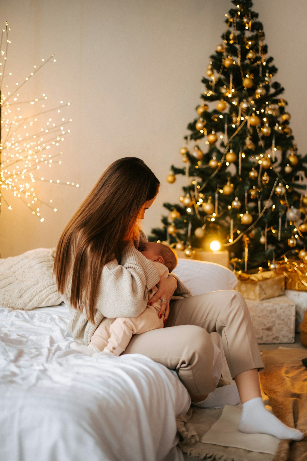 a woman sitting on a bed holding a baby