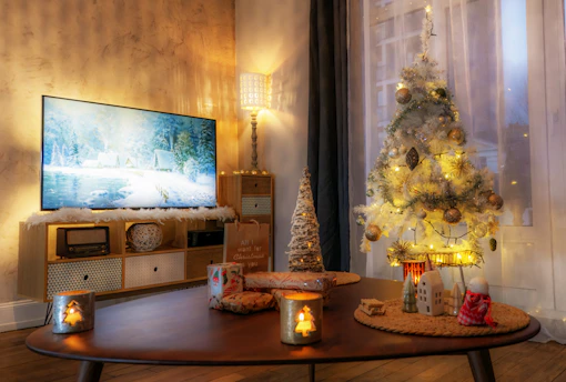 A cozy living room decorated with a glowing Christmas tree and festive ornaments.