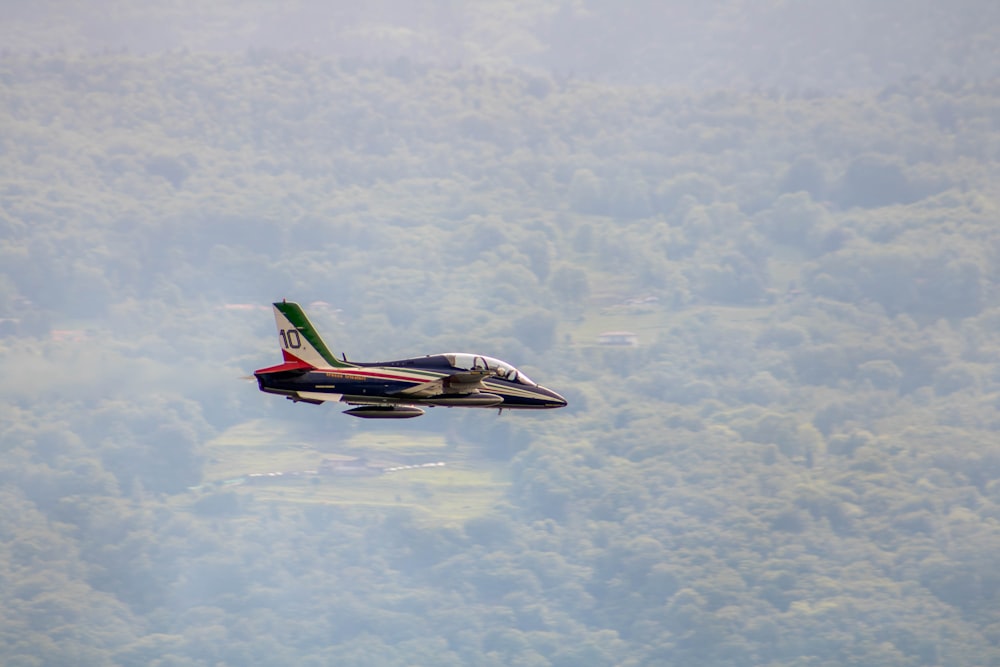 a fighter jet flying over a lush green forest