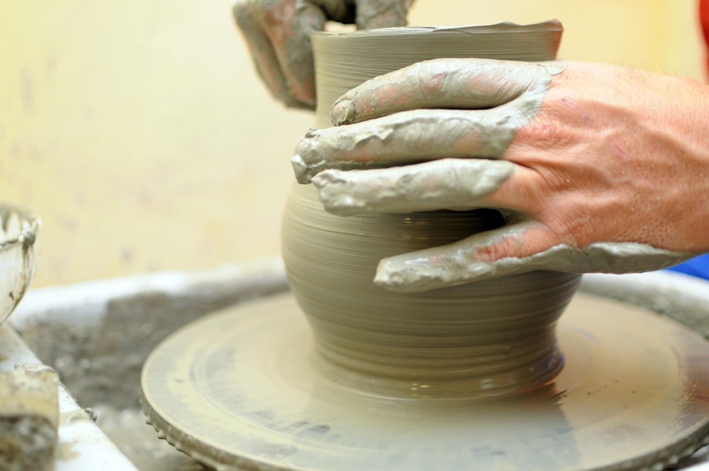 a person making a vase on a potter's wheel