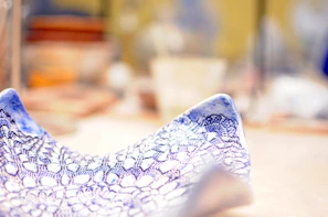 Close-up of a delicate ceramic plate with a subtle blue glaze, resting on a wooden table.