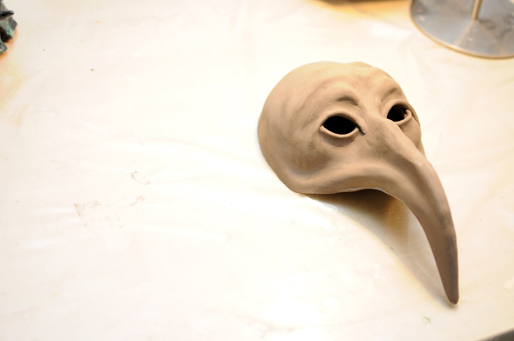 a white mask with a long beak on a table