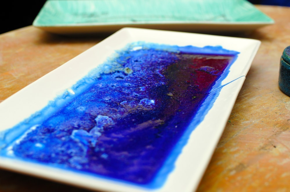 a white plate topped with blue and purple liquid