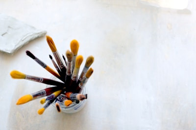 Close-up of colorful paintbrushes with wooden handles arranged in a rustic jar.