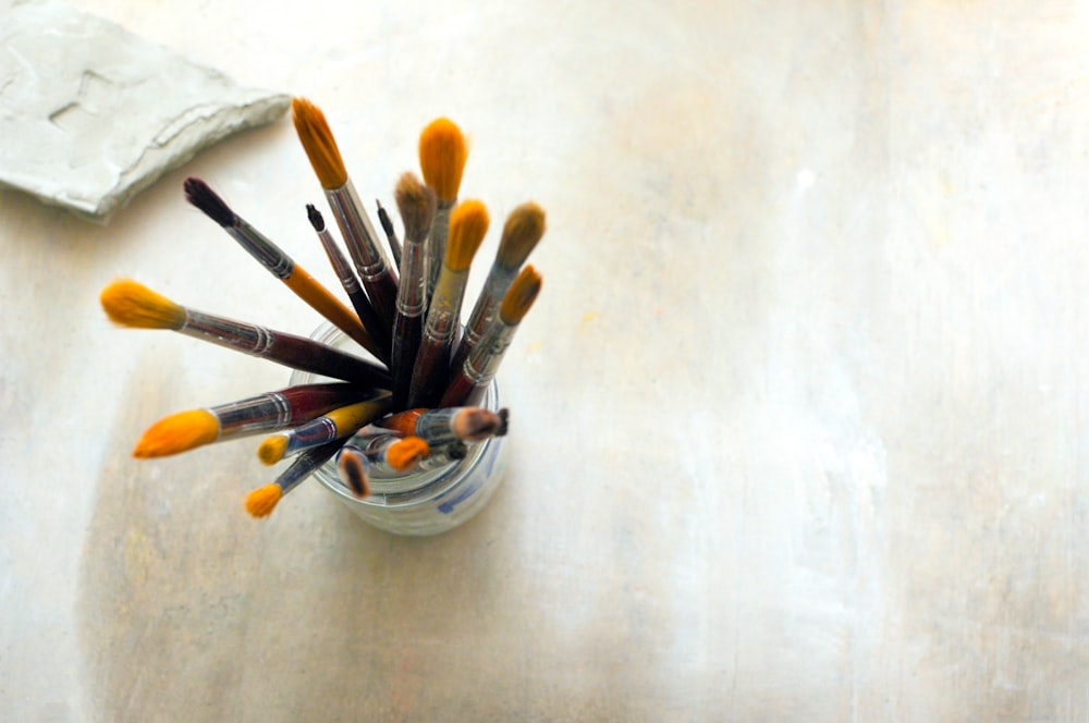 a glass filled with lots of paint brushes