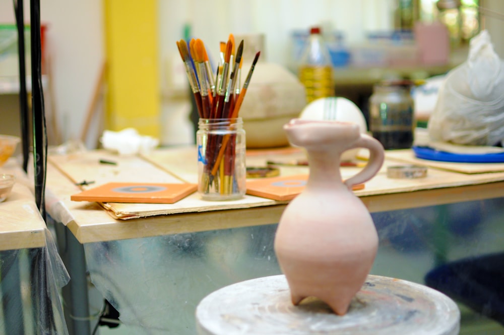 a white vase sitting on top of a wooden table