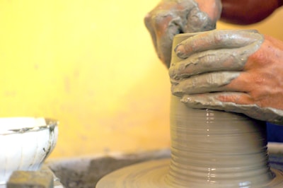 Close-up of hands shaping clay on a pottery wheel in a warm studio