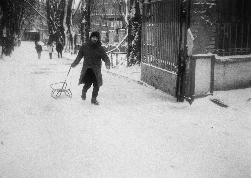 a woman walking down a snow covered street with a sled