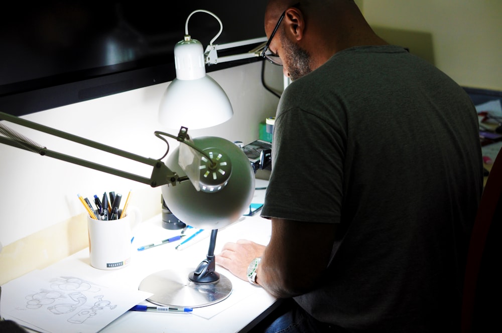 a man sitting in front of a desk with a lamp on it