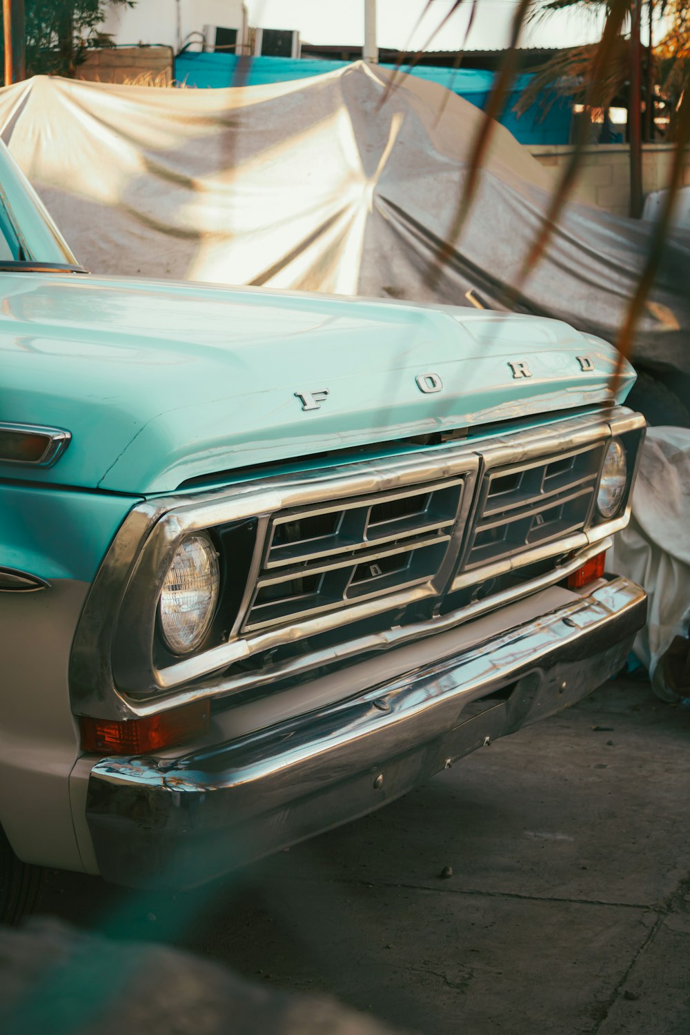 a blue truck parked next to a tarp covered building