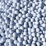 Close-up of hands sorting clean recycled golf balls on a wooden table.