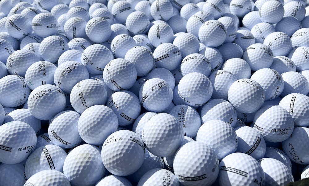 a large amount of white golf balls are stacked on top of each other