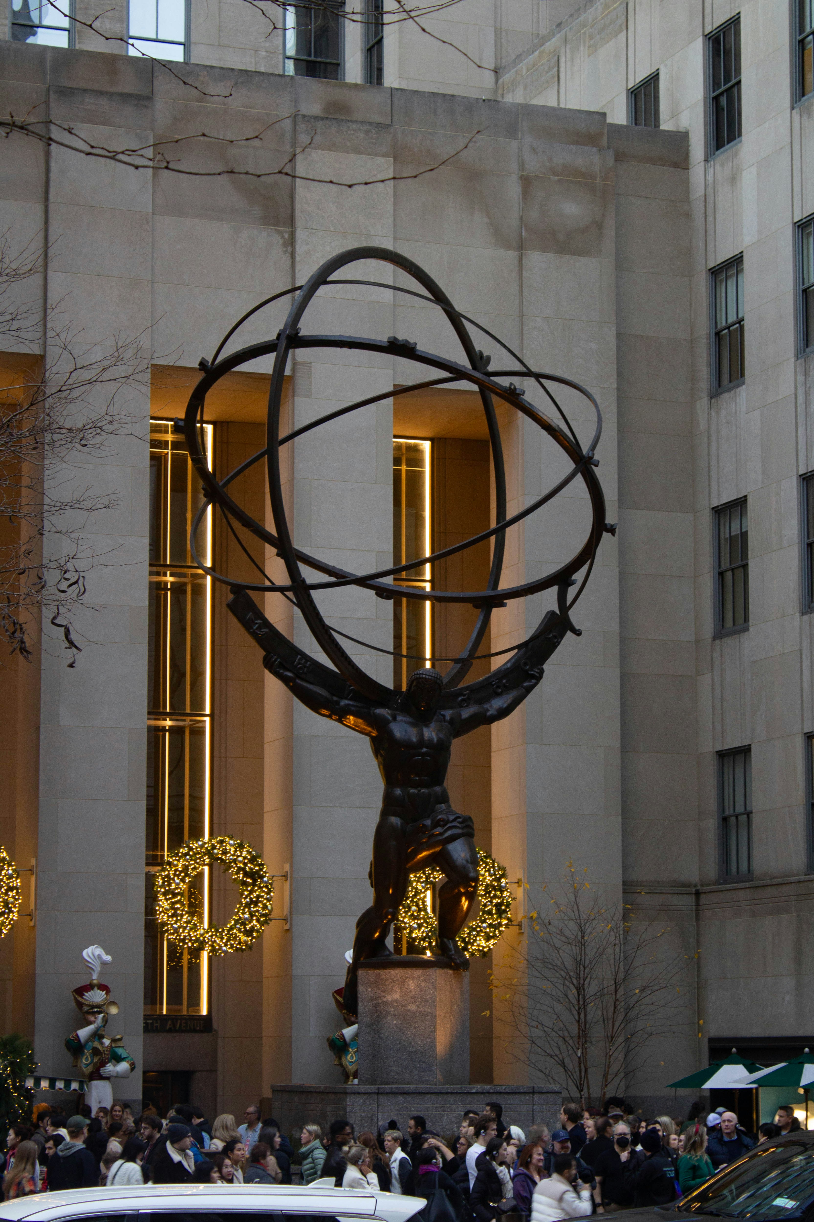 a statue in front of a building with people walking around