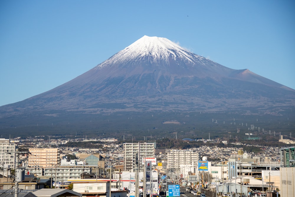 a large snow covered mountain towering over a city