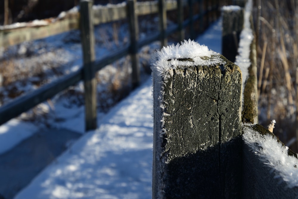 a wooden fence with snow on top of it