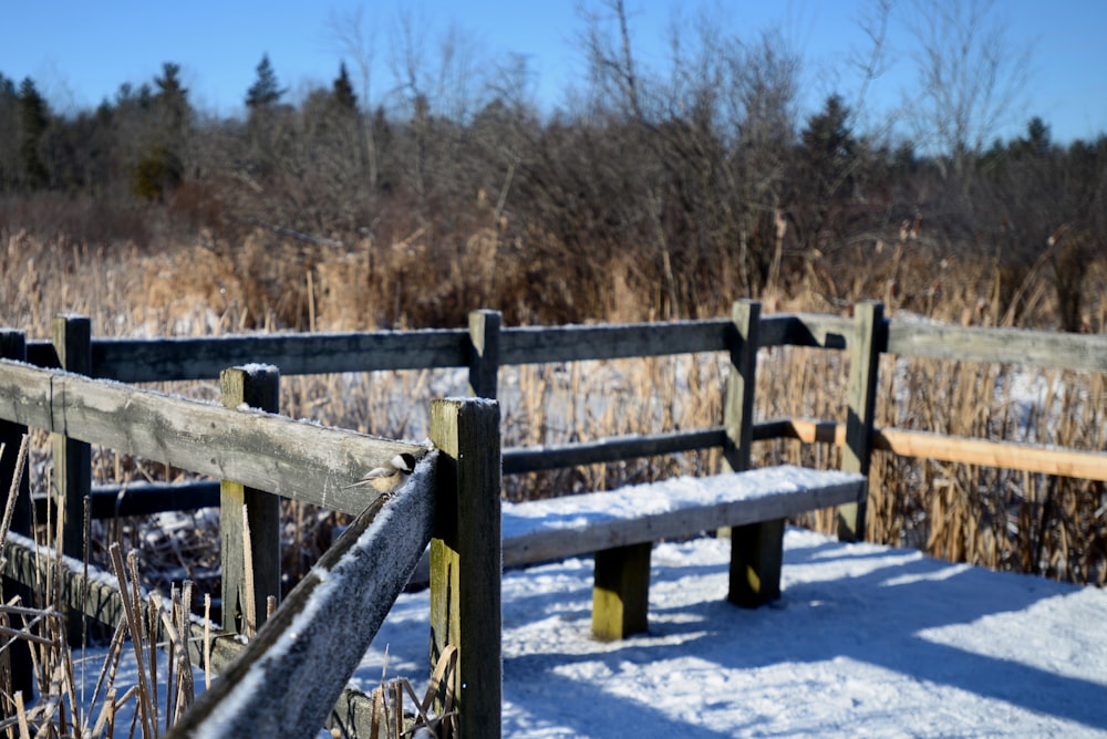 a wooden bench sitting in the middle of a snow covered field