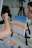 An artist is painting a canvas on an easel. The canvas depicts a gradient sky with shades of blue, orange, and white, resembling a sunset. The artist's hand is holding a brush, applying more paint. A palette with various colors is on the table, including orange, yellow, and blue. In the background, a person appears to be looking at the artwork.