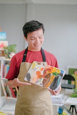 A friendly painter in a bright, freshly painted room holding a paint roller and smiling.
