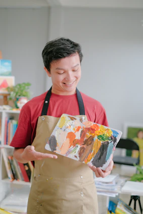 A smiling technician carefully painting a kitchen cabinet in a bright Georgetown home.