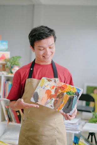 Smiling homeowner pointing at a freshly painted wall while the handyman cleans up.
