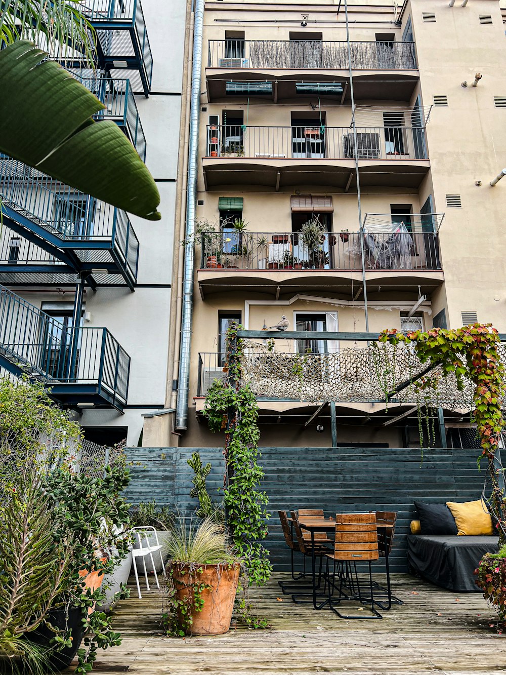 a patio with a table and chairs next to a tall building