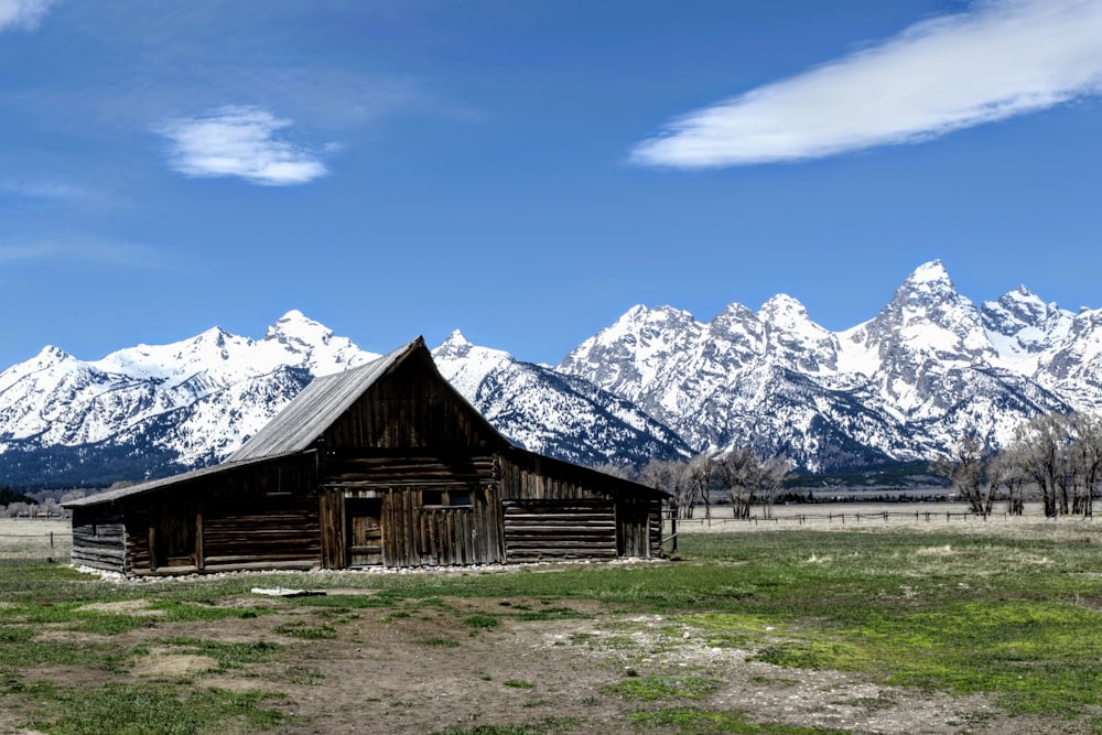 une grange dans un champ avec des montagnes en arrière-plan