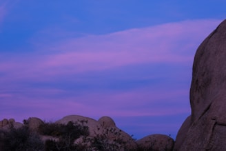 A serene landscape blending granite, blue sky, and sandy textures symbolizing resilience and nature's cycle.
