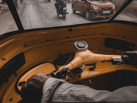 A learner behind the wheel of a car navigating Bengaluru traffic with an instructor beside them.