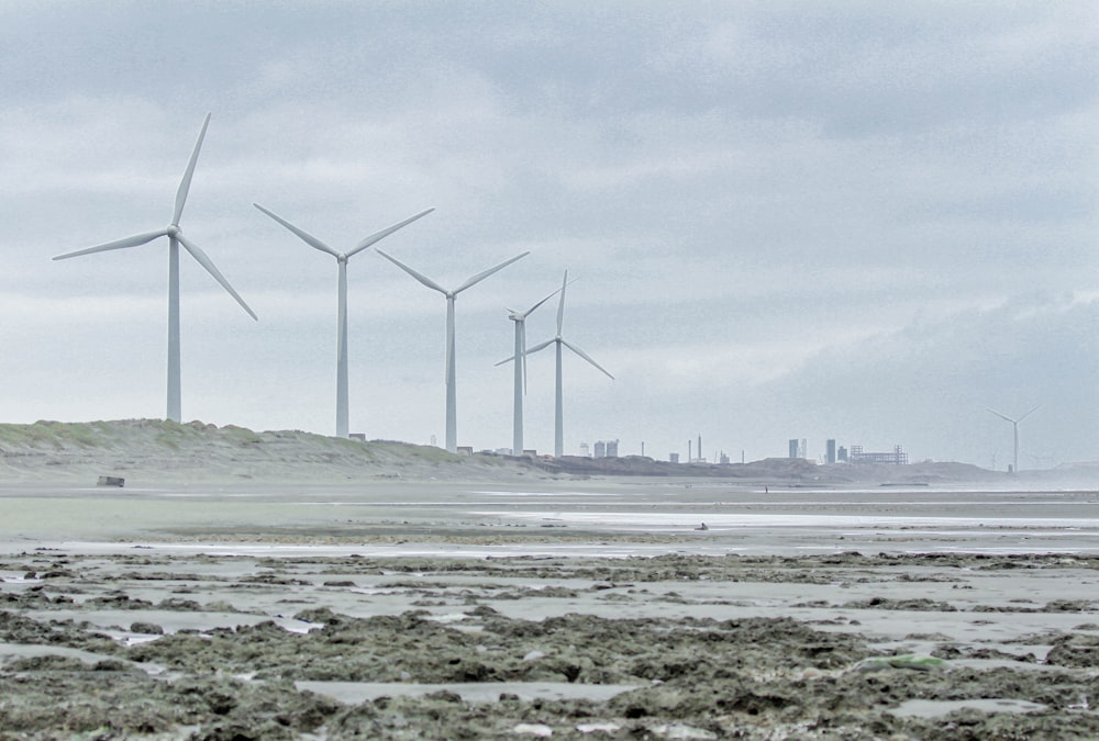 a group of wind turbines sitting on top of a sandy beach