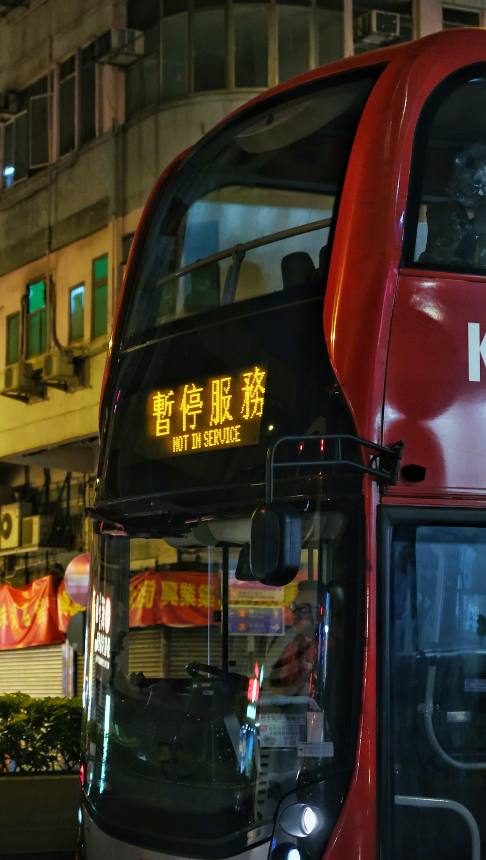 a red double decker bus driving down a street