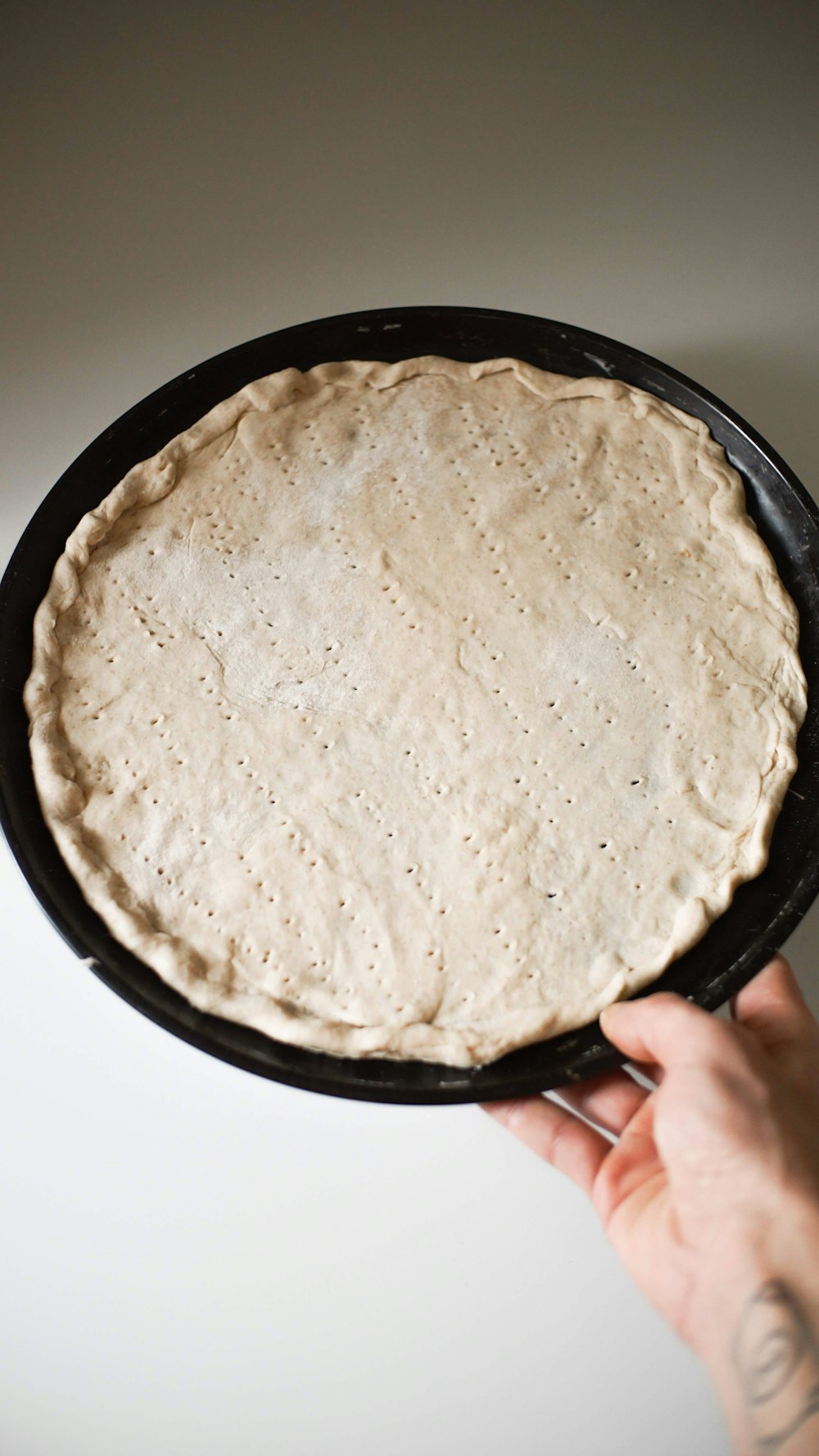 a person holding a pan with a pizza crust in it