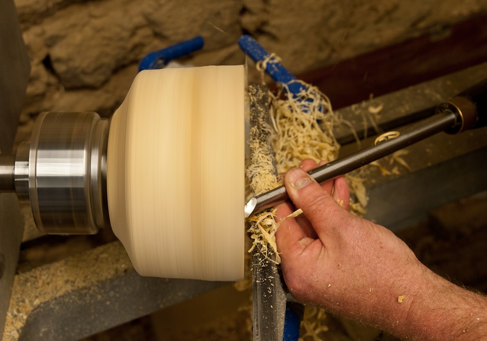 a man is working on a machine with a piece of wood