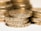 A close-up shot of several stacked gold coins with detailed engravings visible on their edges.