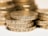 A close-up shot of several stacked gold coins with detailed engravings visible on their edges.
