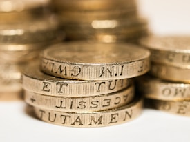 A close-up shot of several stacked gold coins with detailed engravings visible on their edges.