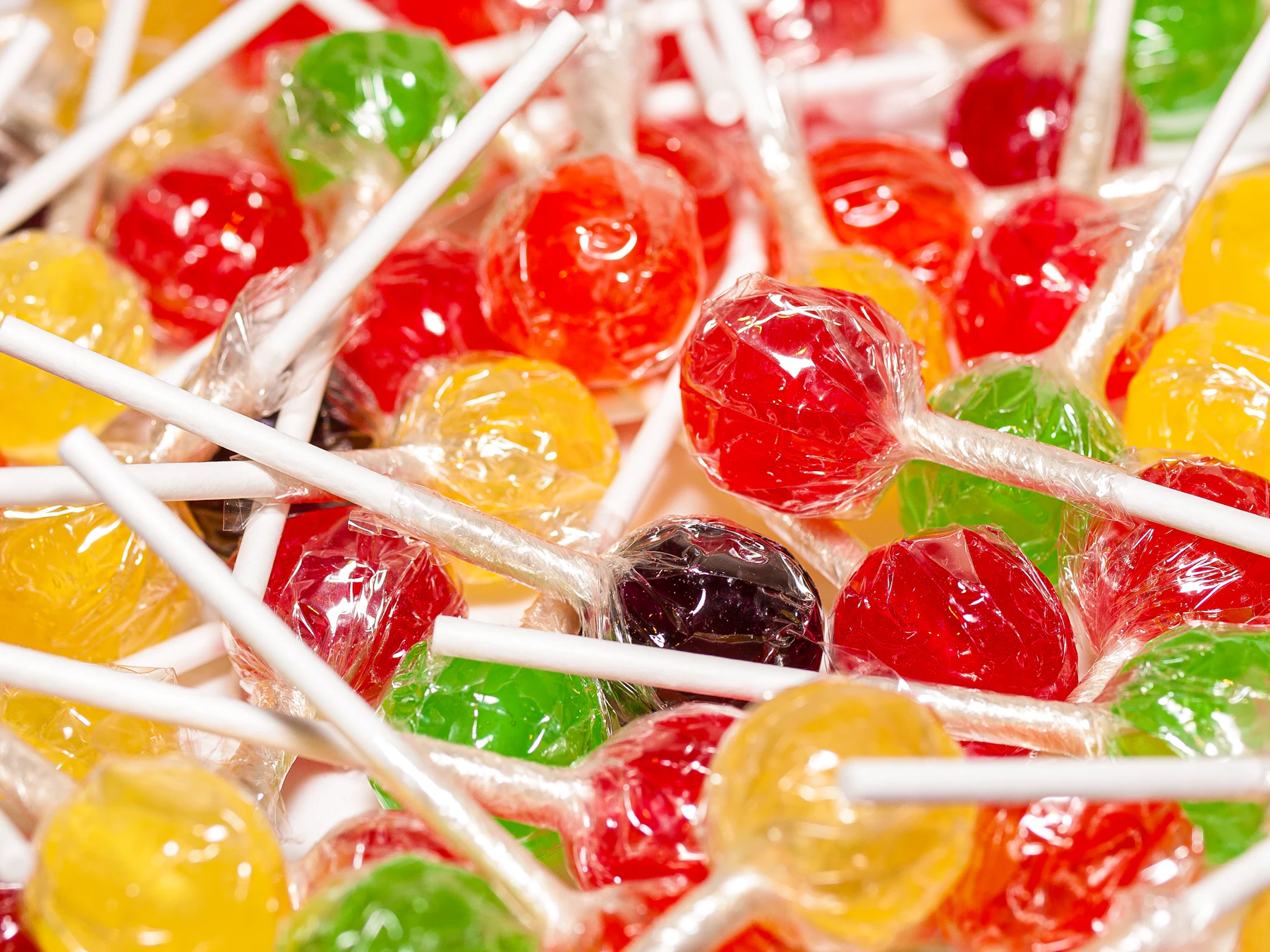 A heap of round red, yellow and green hard-candy lollipops in clear wrappers