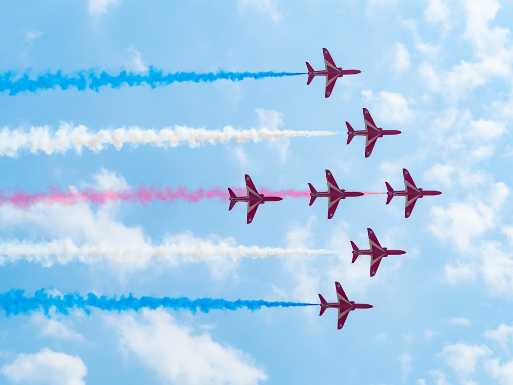 a group of jets flying through a blue cloudy sky