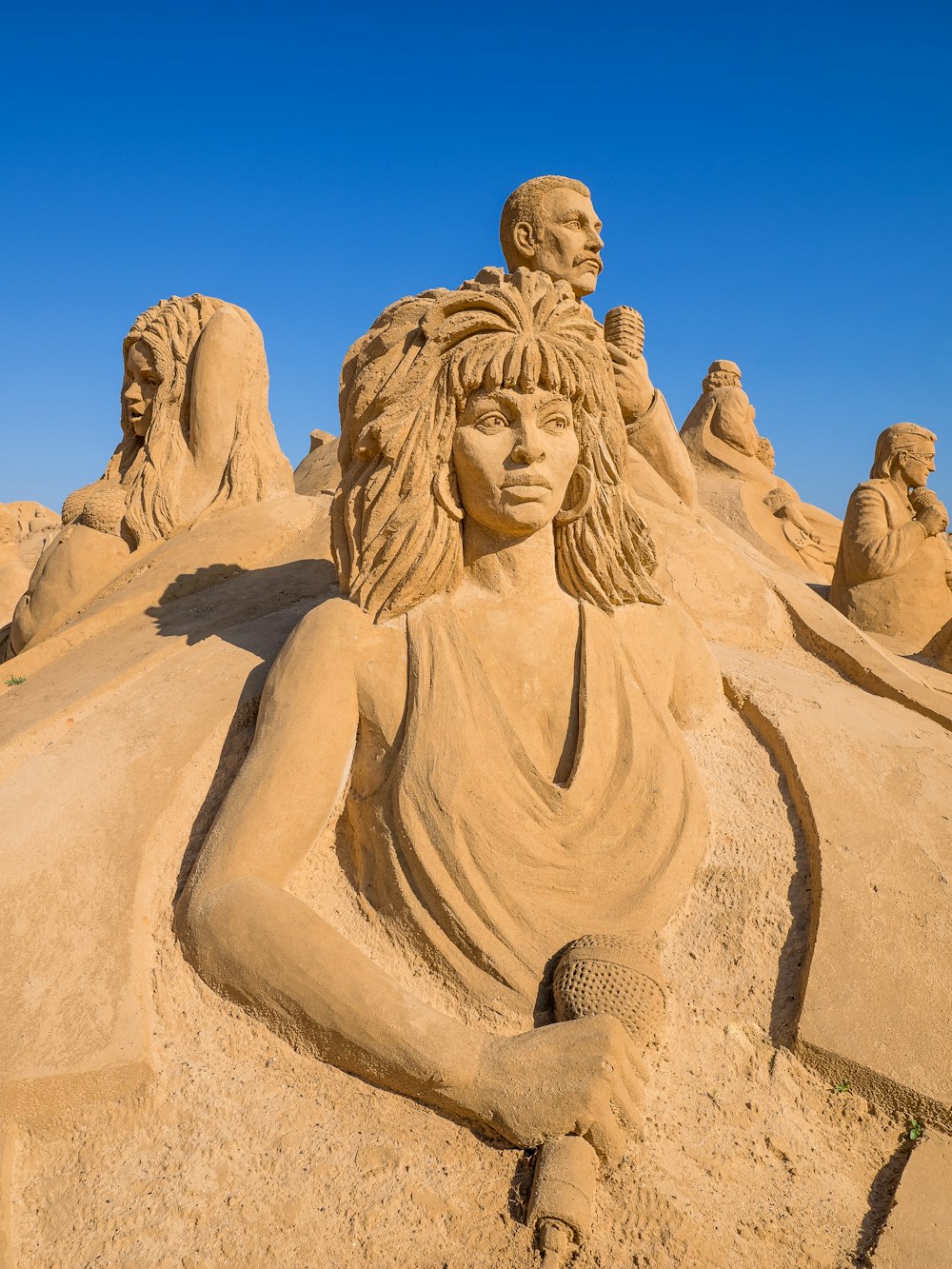 eine Sandskulptur einer Frau, die im Sand sitzt