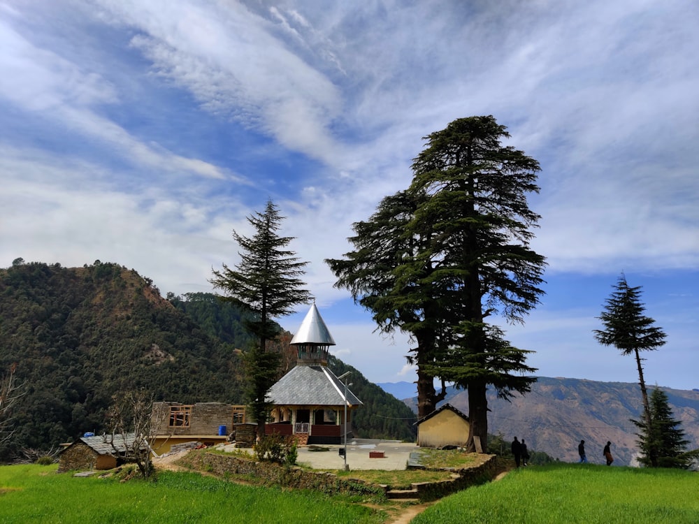 a small building on a grassy hill with trees in the background