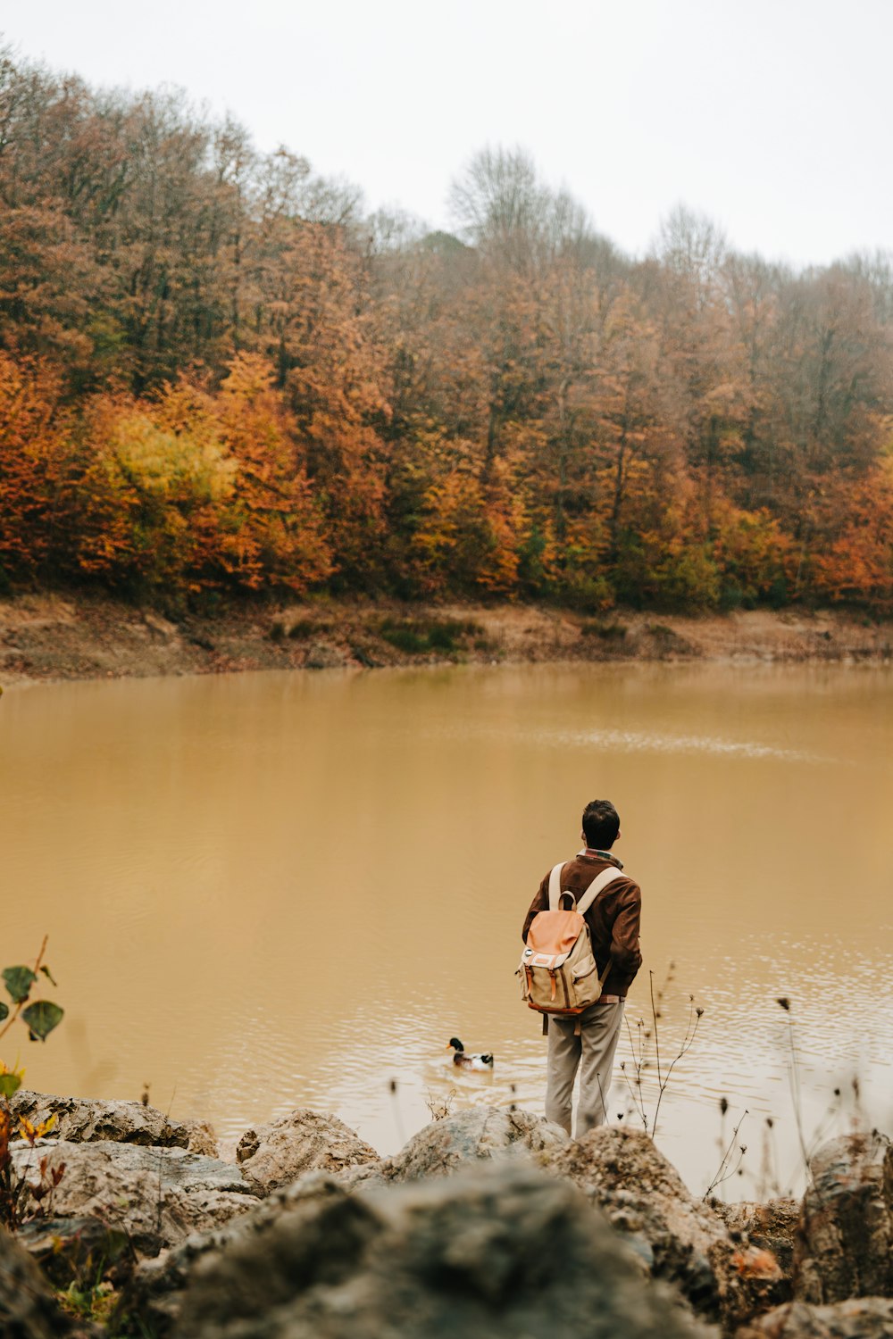 a man with a backpack standing in front of a lake