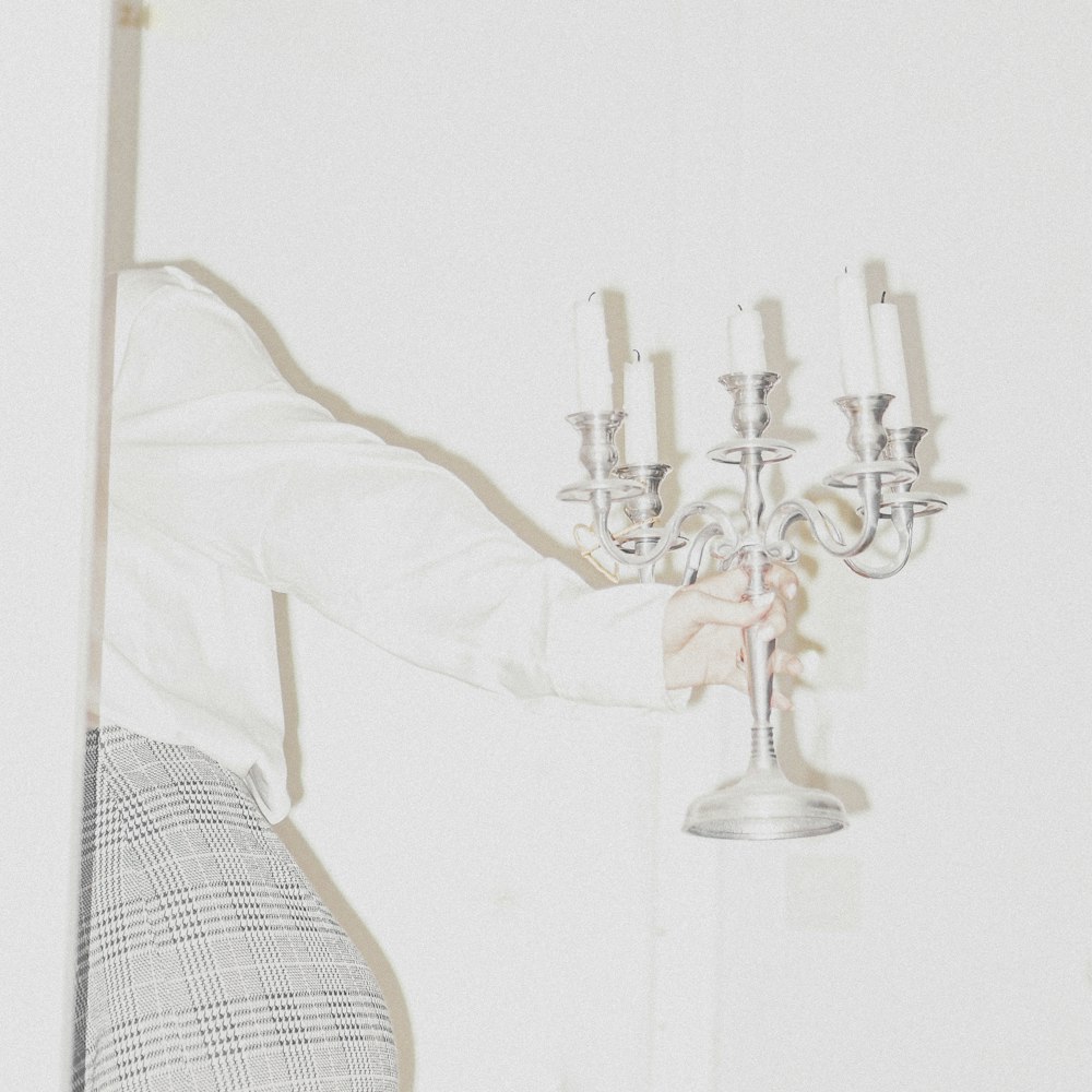 a woman holding a candelabra in front of a white wall